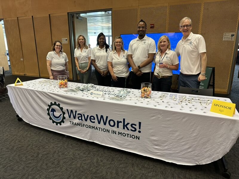 Group photo of 7 people standing by WaveWorks table